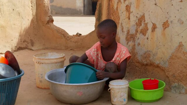 Little cute black african child children washing dish in remote rural village of Africa