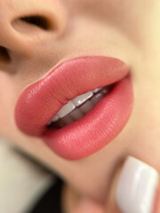 permanent makeup on the lips of a young woman of a delicate peach shade close-up, a girl after a cosmetic procedure with smooth and clean healthy skin.