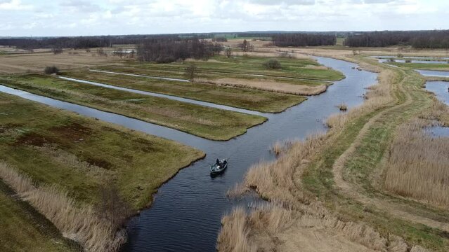 Watch as a boat gracefully navigates the tranquil waters, surrounded by lush greenery and charming countryside scenery.
