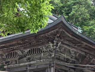 A landscape with the intricately designed wooden eaves of a traditional architectural structure, surrounded by lush greenery.