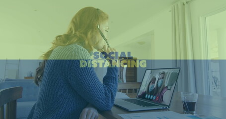 Image of social distancing text over woman using laptop on image call