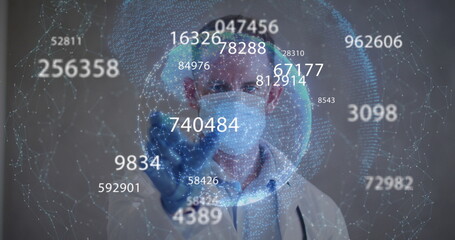 Image of statistics recording and globe over male doctor wearing gloves and face mask