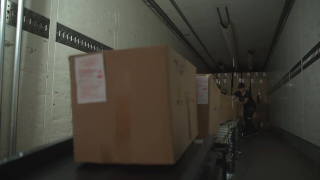 Male workers loading truck with lots of cardboard boxes filled with products. Workers loading the huge truck for item transportation. Workers loading truck before shipping the goods.