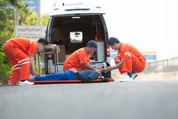 The paramedic  is assisting an injured man in an emergency situation on the road. - obrazy, fototapety, plakaty