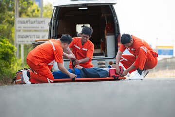 The paramedic  is assisting an injured man in an emergency situation on the road.