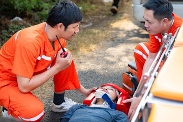 The paramedic  is assisting an injured man in an emergency situation on the road.