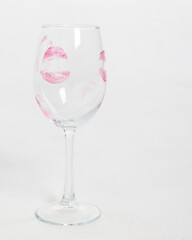 Empty wine glass with lip print on white background. Vertical photo. High quality photo