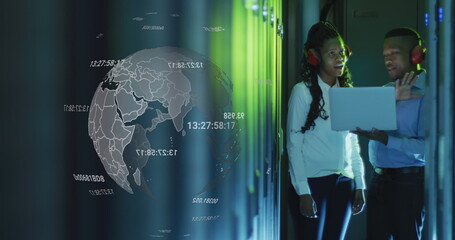 Image of globe over african american man and woman working with laptop and servers