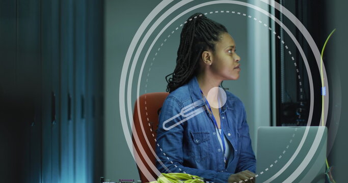 Image of clock moving over biracial woman working in servers room
