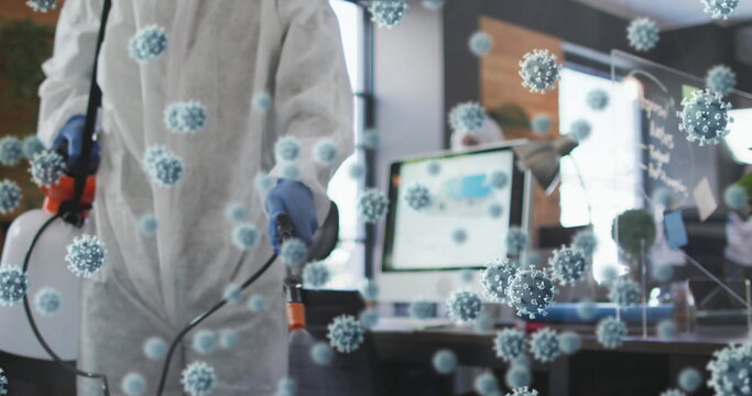 Multiple covid-19 cells floating against male health worker spraying disinfectant at office