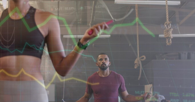 Image of data processing on graph over diverse woman and man jumping rope cross training at gym