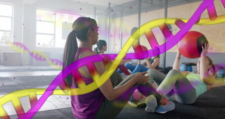 Image of dna strands over diverse women cross training in pairs with medicine balls at gym