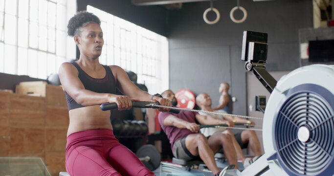 Young African American woman exercises on a rowing machine at the gym