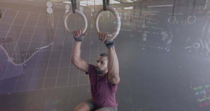 Image of graph processing data over biracial man cross training on gym rings at gym