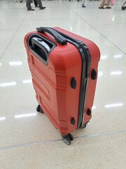 A red suitcase with black lines on the zipper and wheels is very suitable for long trips or travel