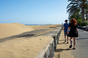 Two teenagers run on a path next to sand dunes