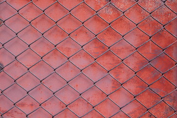 Chain link fencing mesh or wire gauze  front red painted and decay with rusty surface metal background.