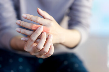 A woman touches a red area on her finger to indicate the pain point.