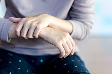 A woman touches her arm or wrist because of pain from a health problem. Health care concept.