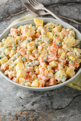 Brazilian gaucho potato salad brings together the best summer flavours from potatoes and grilled sweetcorn, to peas, carrots and apples closeup on the plate on the marble table. Vertical