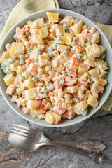 Brazilian gaucho salad is made with a combination of potatoes, carrots, peas, corn, green apples and mayonnaise closeup on the plate on the marble table. Vertical top view from above