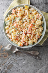 Brazilian gaucho potato salad brings together the best summer flavours from potatoes and grilled corn, pea, carrot and apples closeup on the plate on the marble table. Vertical top view from above