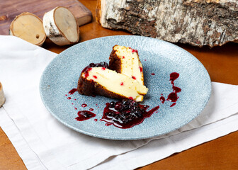 Cheesecake with jam in a plate on a wooden background