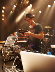 Music, DJ and spotlight on man at stage with headphones and equipment for performance on sound...