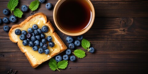 Tasty toasts with butter, blueberries, and coffee on a wooden table, top view.