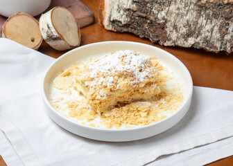 Napoleon cake in a plate on a wooden background