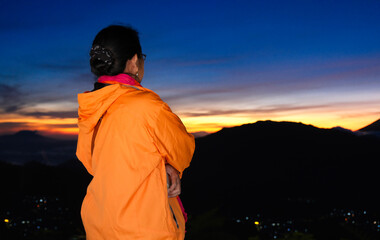 Rear view: A woman waits for the sun to rise up from behind Mount Sindoro