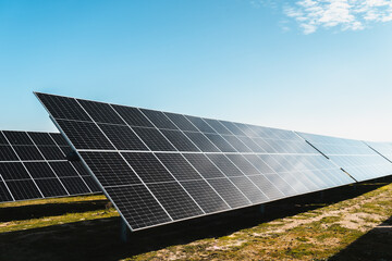 detail profile view of row of solar panels in photovoltaic solar energy park on bright sunny day