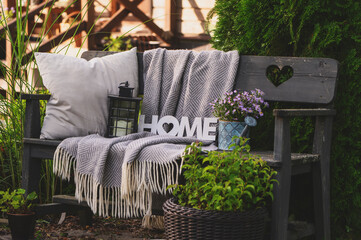 pillows and blanket on cozy rustic wooden bench in summer garden. Country living.