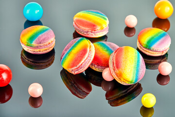 Close-up of a delicious and colorful rainbow-colored macarons placed separately on a gray surface,...