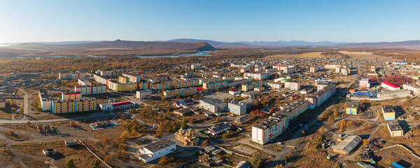 Aerial view of the northern urban-type settlement of Ola. Top view of the streets and buildings. Wide panorama. Ola is the administrative center of the Olsky district of the Magadan region. Russia. - obrazy, fototapety, plakaty
