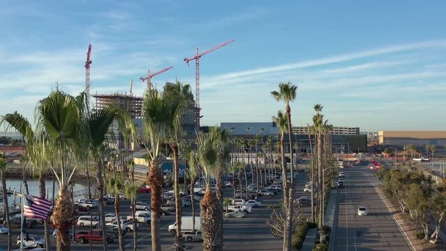 The new convention center being build in Chula Vista California, drone rising from behind palm trees.