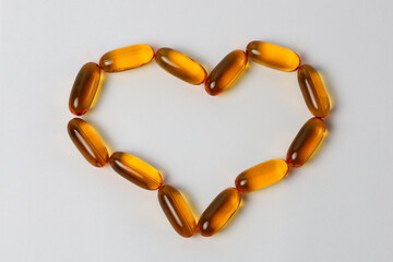 Omega-3 capsules laid out in the shape of a heart on a white background