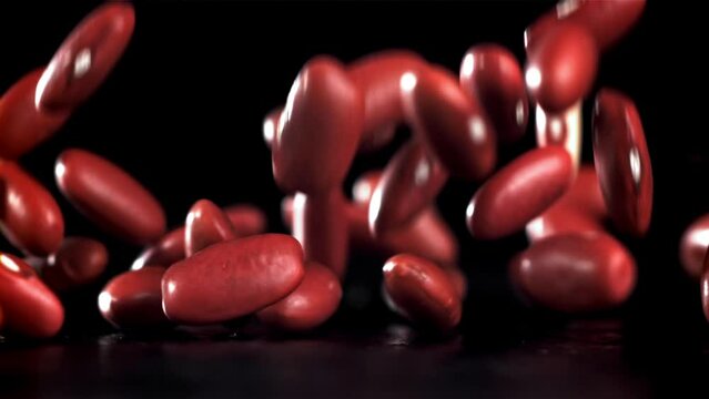 Falling red beans on a black background. Filmed on a high-speed camera at 1000 fps. High quality FullHD footage