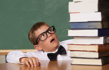 Child, surprise and stack of books in classroom for education, language learning and knowledge with wow for studying list. Kid or student with glasses and shocked for school literature and textbook