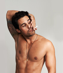 Shirtless, cigarette and man smoking in a studio for grungy, cool and attractive personality....