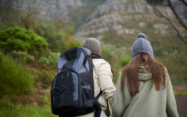 Outdoor, hiking and couple in mountain, holding hands and walking with backpack, nature and bonding together. Forest, adventure and trekking in path, field and exercise for fitness and travel