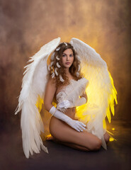 A girl with large white angel wings covers her nakedness with a feather