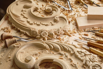 In the workshop, a woodcarver sculpts floral patterns into the heart of a wooden block. Warm hues...