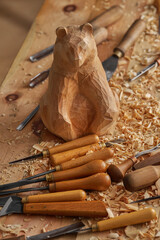 Wood carving, Unfinished bear sculpture emerges under warm illumination. Carving tools and wood...
