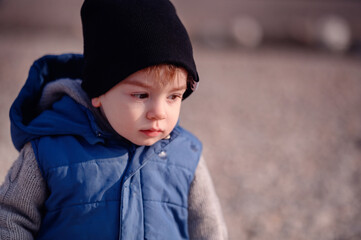 Thoughtful young child in a knit sweater and vest, contemplating during a cool outdoor day