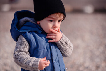 Thoughtful young child in a knit sweater and vest, contemplating during a cool outdoor day