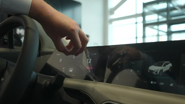 A man removes the protective film from the dashboard of a new car. 