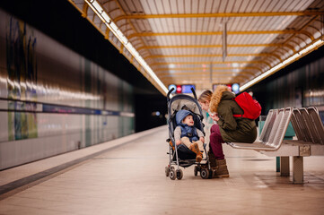 Joyful Interaction at Metro Station. Young mother and laughing toddler enjoy a playful moment while waiting for the metro