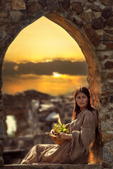 Pretty woman in the Middle Ages at a castle in the sunset