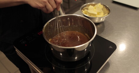 Adding and mixing butter to chocolate mousse to make a dessert. Chocolate preparation, professional kitchen, baking, confectionery